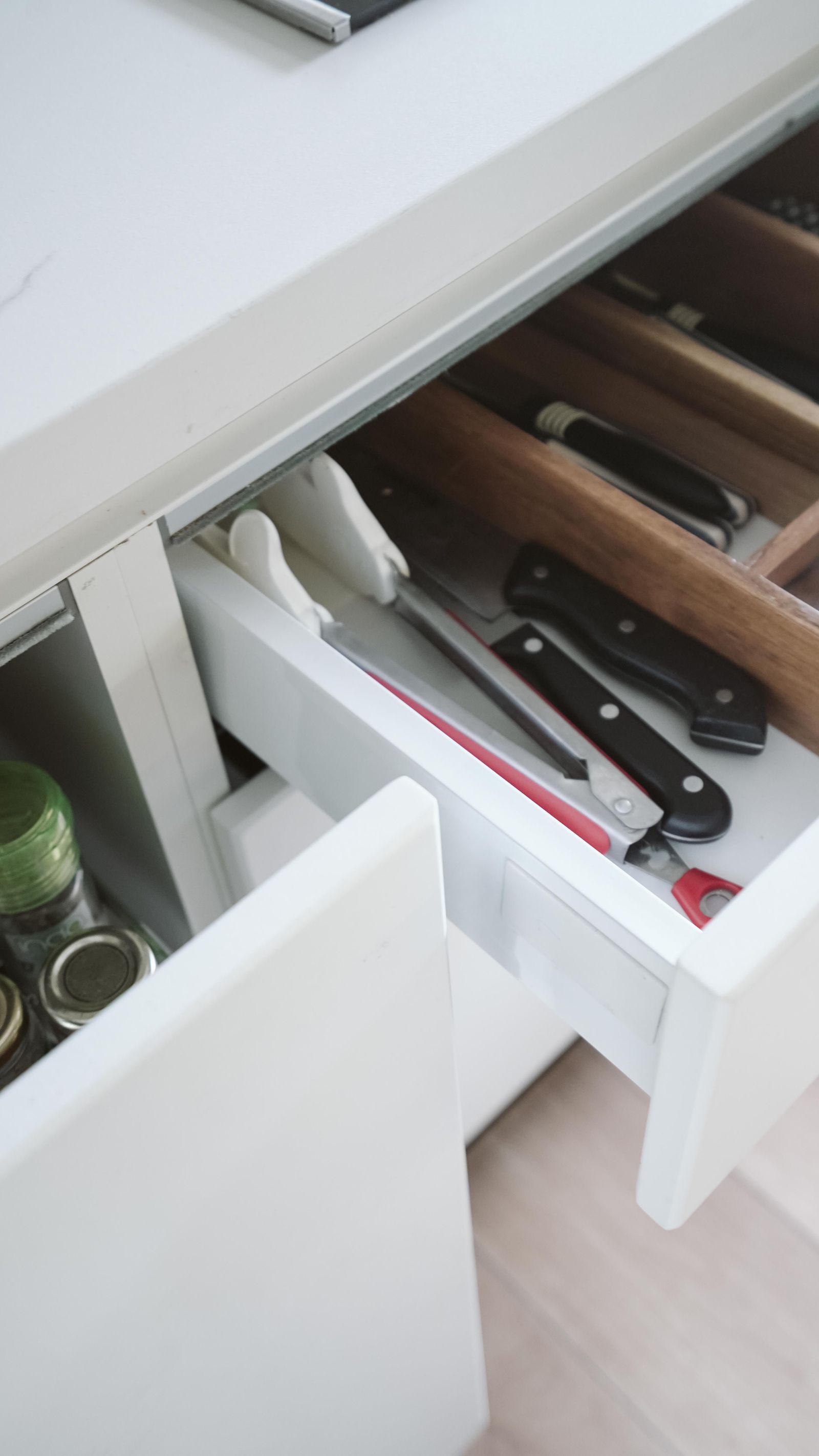 Open kitchen drawer with wooden dividers and kitchen utensils