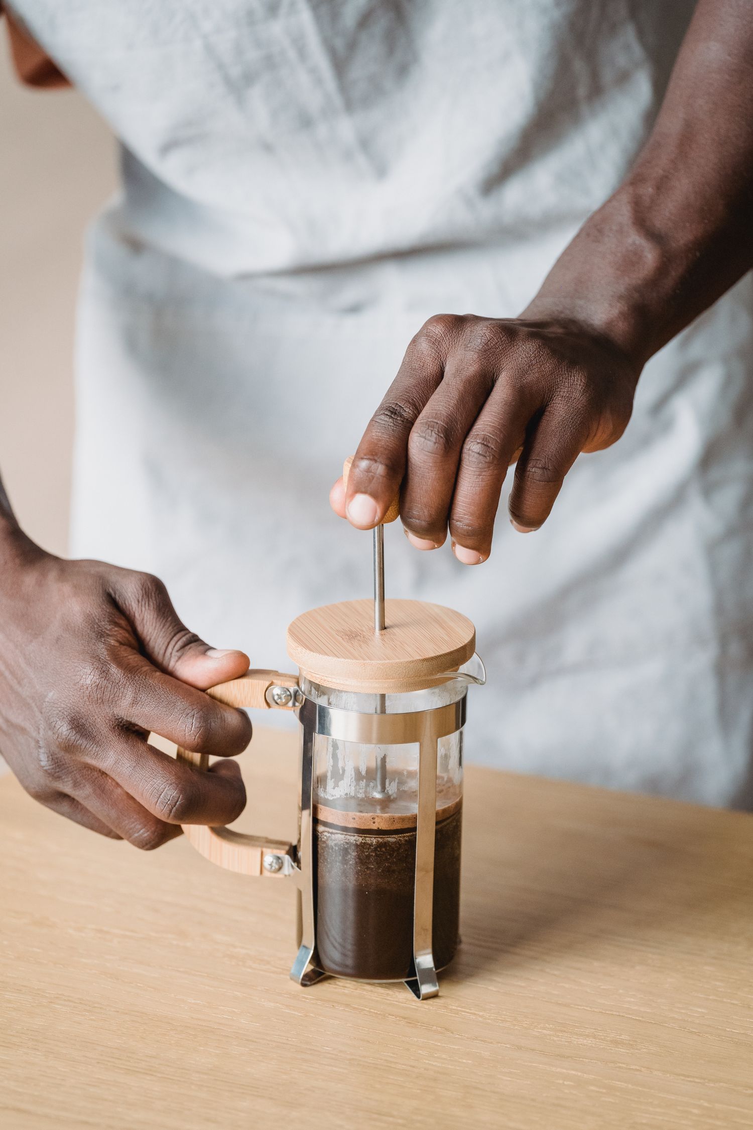 Person pressing the plunger of a French press