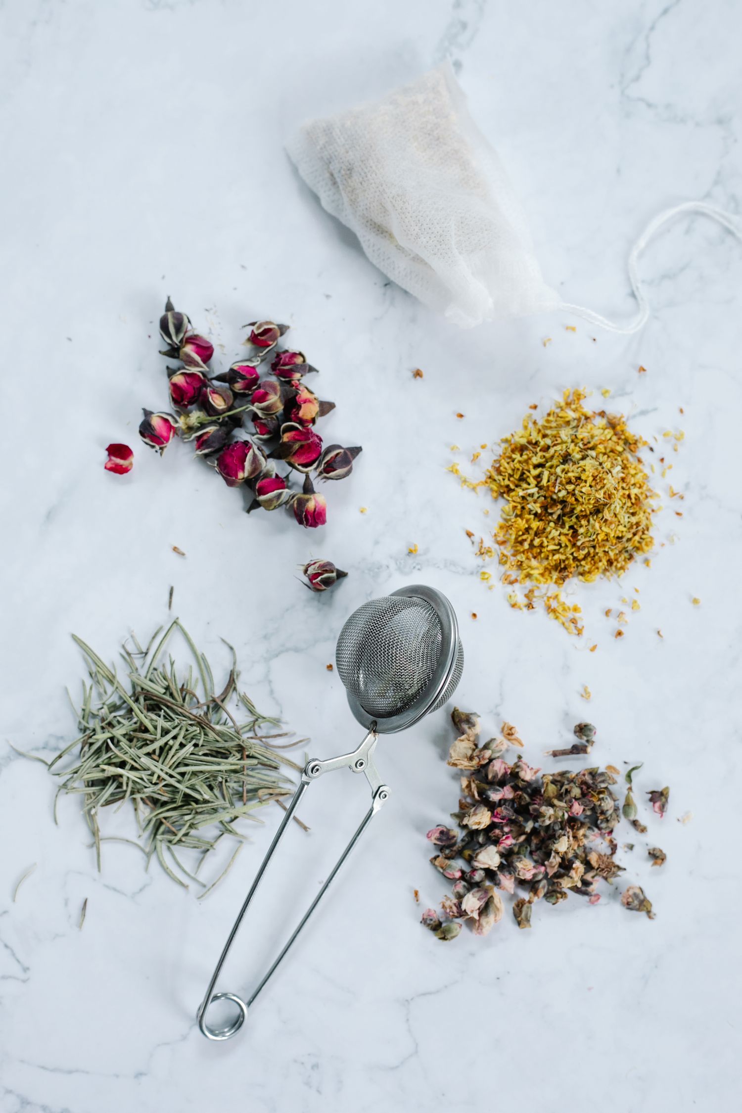 Metal tea infuser beside loose tea ingredients