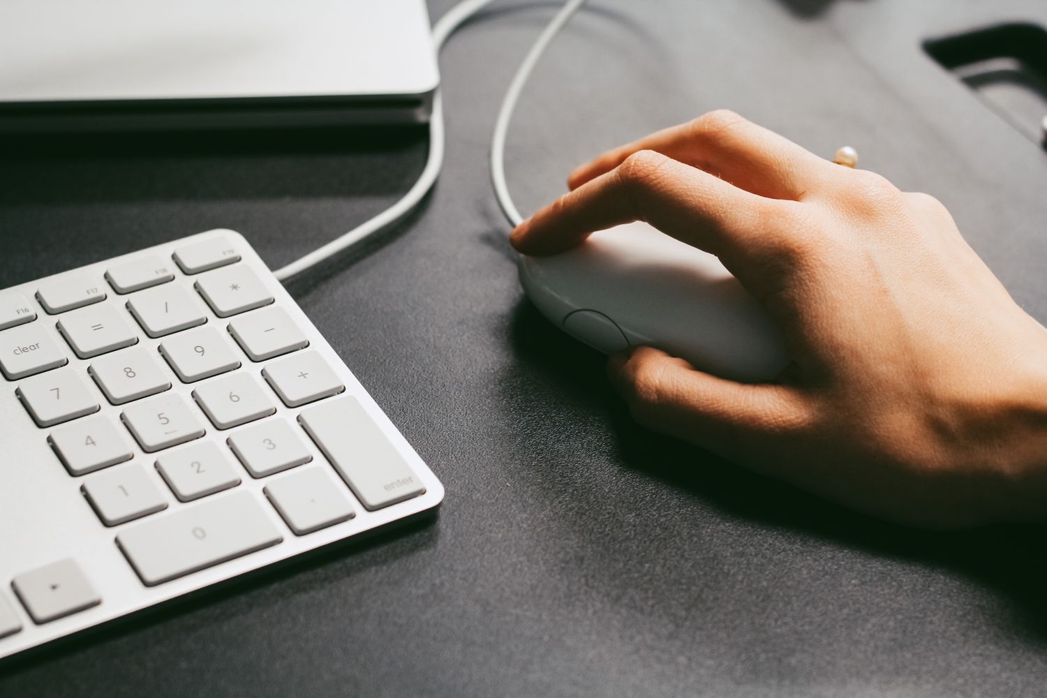 Hand operating a computer mouse beside a keyboard