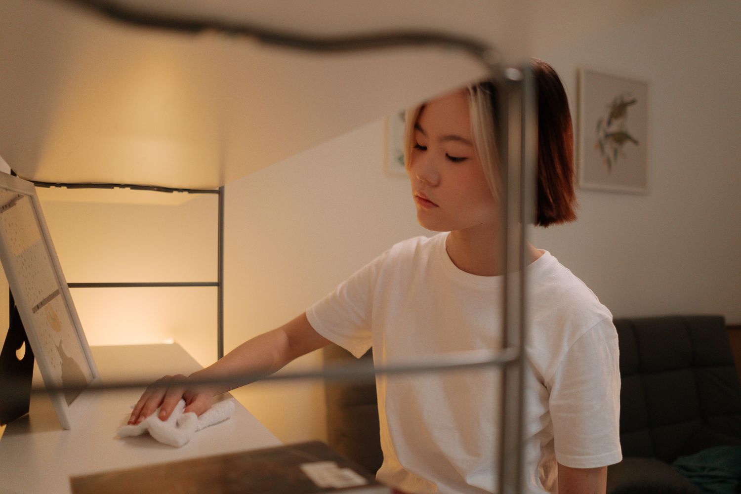 Person wiping a shelf with a cleaning cloth