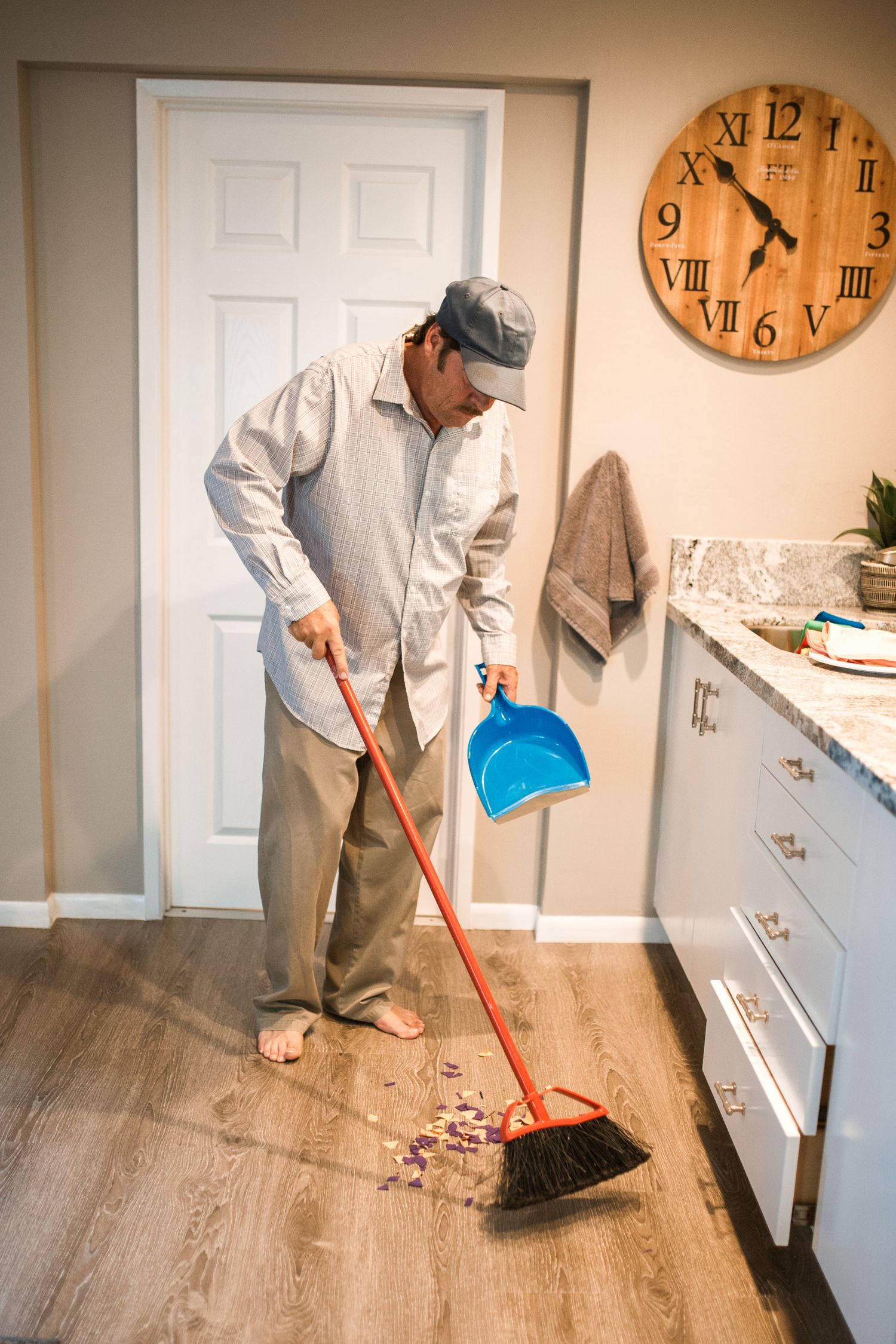Person sweeping a kitchen floor with a broom