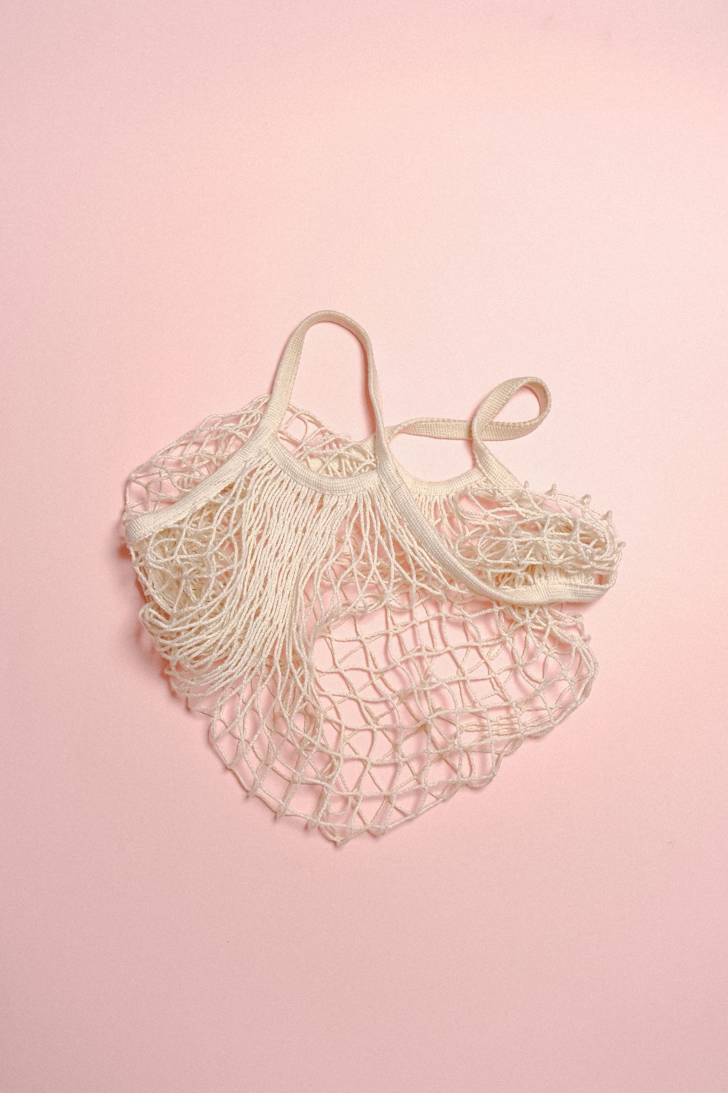 Reusable mesh shopping bag on a pink background